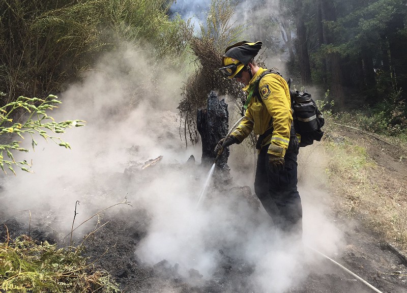 Novato Fire District firefighter Kyle Marshall sprays a spot while fighting fires in Big Sur, CA. CREDIT: AP PHOTO/TERRY CHEA